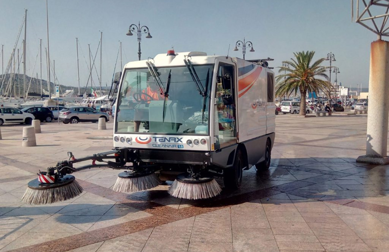 A Tenax electric street cleaner operating on an urban pathway.