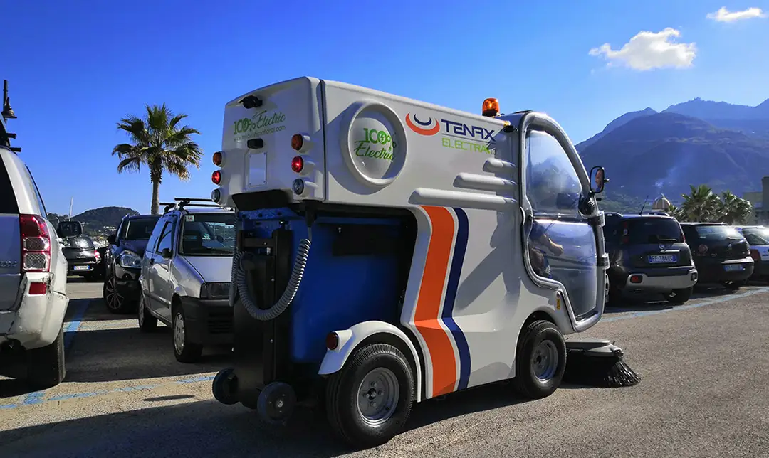 Electra 1.0 compact electric sweeper maneuvering around a parking lot.