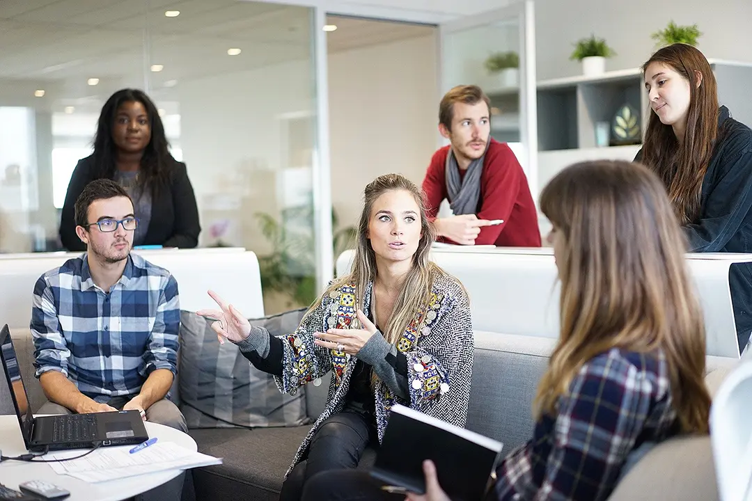 A group of people having a discussion in a modern office setting.